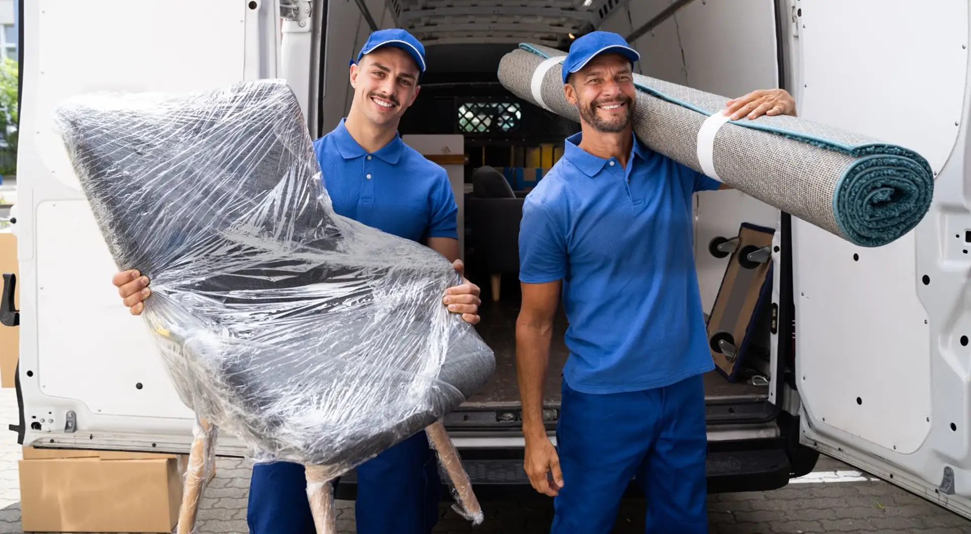 Two smiling licensed movers standing in front of a clean moving truck.